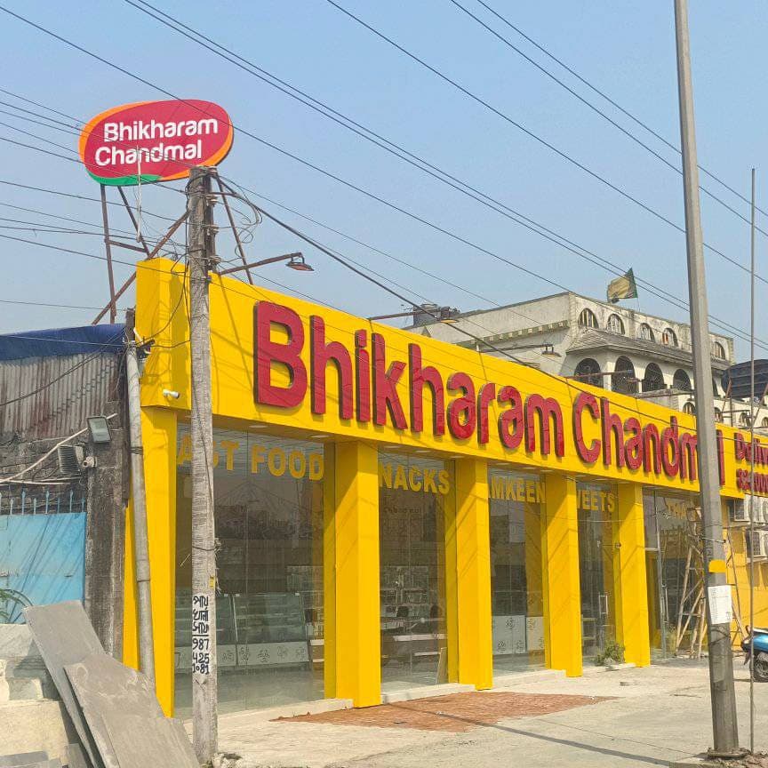 Yellow ACP shop sign board with red lettering on the Bhikharam Chandmal storefront