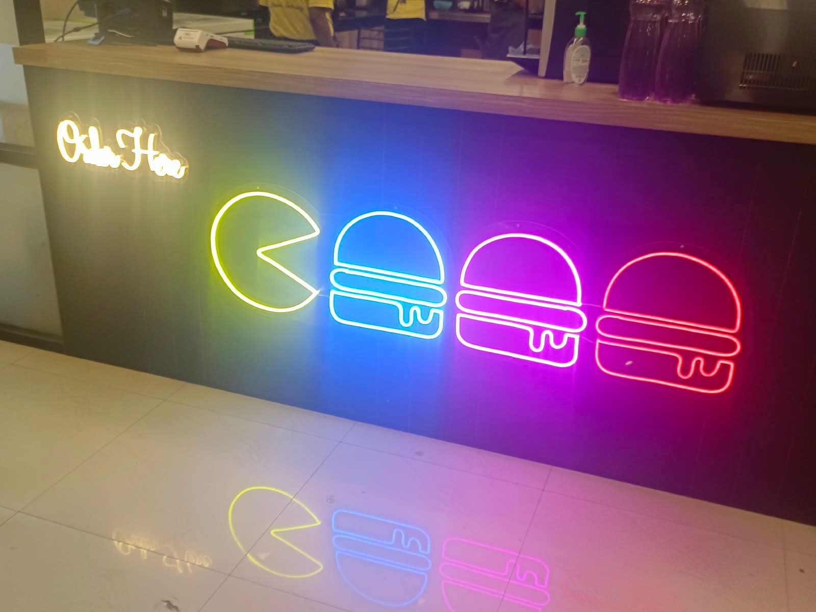 Colourful LED neon burger icons on a restaurant order counter